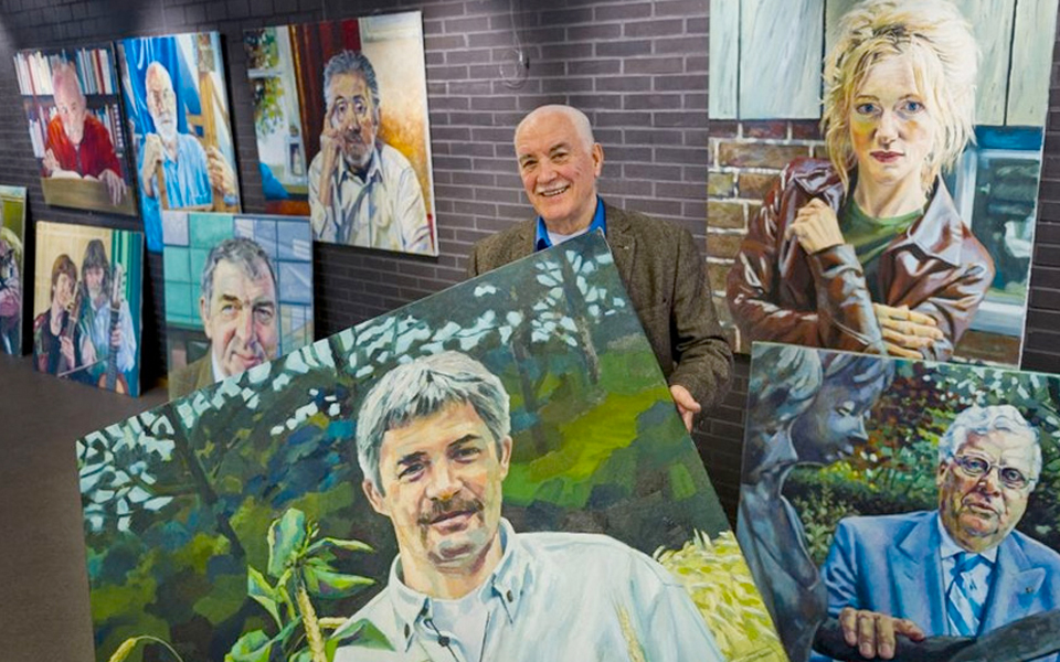 Joep Gierveld met enkele van de portretten die hij maakte van bekende Almeloërs. Foto Wouter Borre